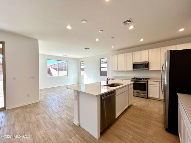 kitchen featuring sink, an island with sink, white cabinets, and appliances with stainless steel finishes