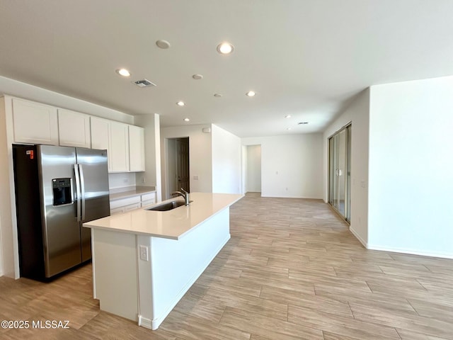 kitchen with white cabinetry, sink, a kitchen island with sink, stainless steel refrigerator with ice dispenser, and light hardwood / wood-style flooring