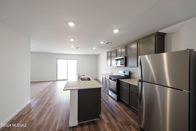 kitchen with appliances with stainless steel finishes, dark hardwood / wood-style floors, sink, and an island with sink