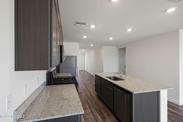 kitchen with dark hardwood / wood-style floors, stainless steel appliances, sink, and a center island with sink