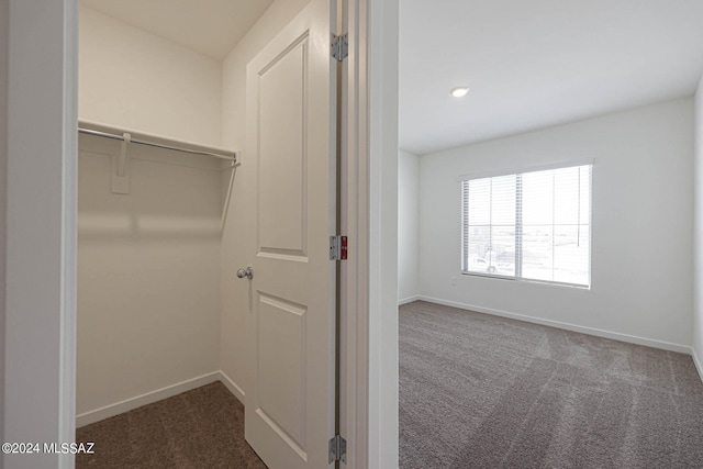 walk in closet featuring dark carpet