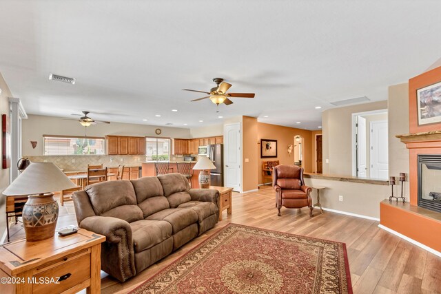 living area with recessed lighting, visible vents, a ceiling fan, light wood-type flooring, and a glass covered fireplace