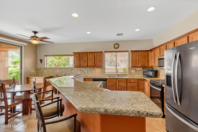 kitchen featuring brown cabinets, light tile patterned flooring, stainless steel appliances, and a sink