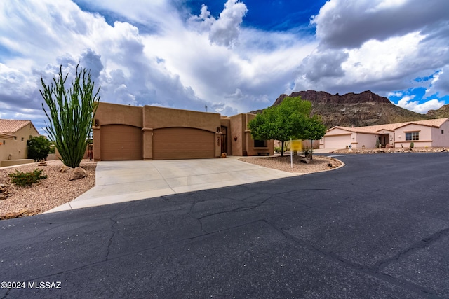 pueblo-style home with stucco siding, driveway, a mountain view, and a garage