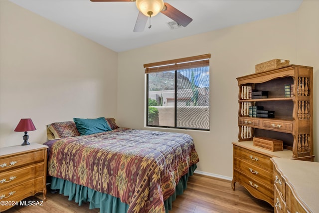 bedroom with baseboards, wood finished floors, visible vents, and ceiling fan