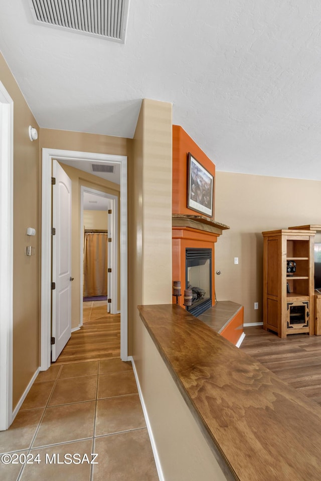 corridor with baseboards, tile patterned flooring, and visible vents