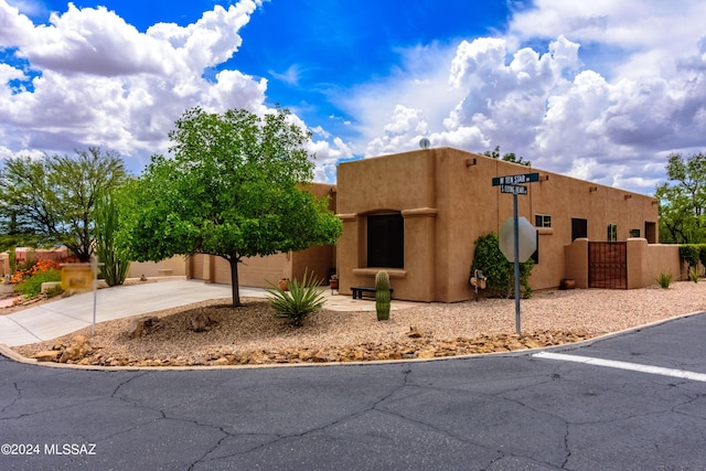 southwest-style home with an attached garage, driveway, a gate, and stucco siding
