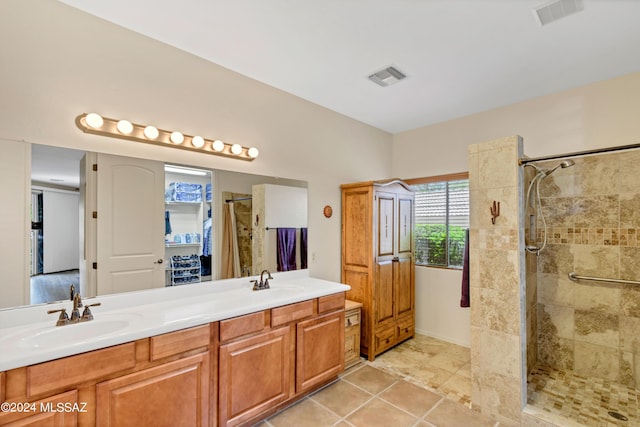 bathroom with a tile shower, a sink, and visible vents