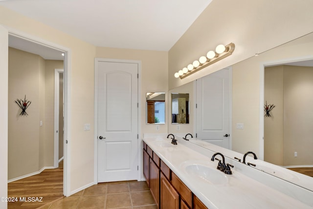 bathroom featuring baseboards, a sink, and double vanity