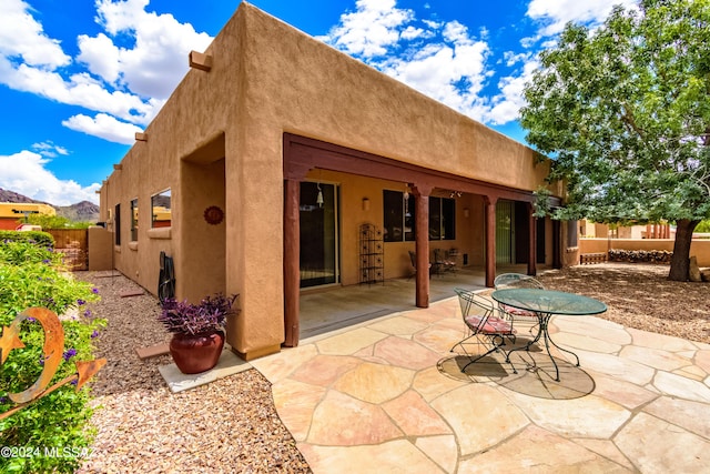 rear view of house with fence, a patio area, and stucco siding