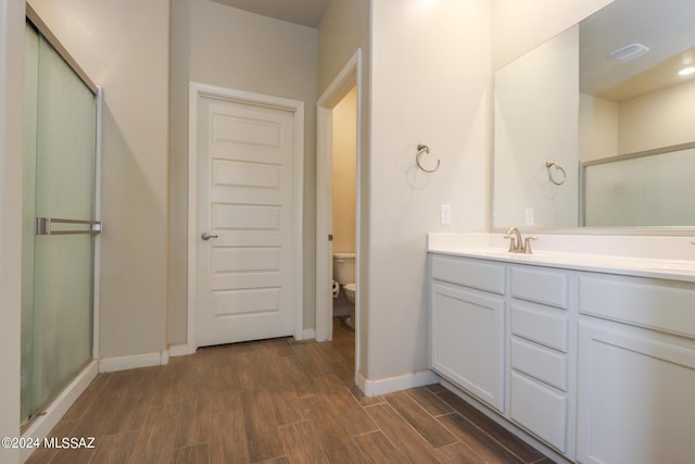 bathroom featuring vanity, a shower with shower door, and toilet