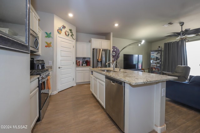 kitchen with dark wood-type flooring, sink, white cabinetry, appliances with stainless steel finishes, and a kitchen island with sink