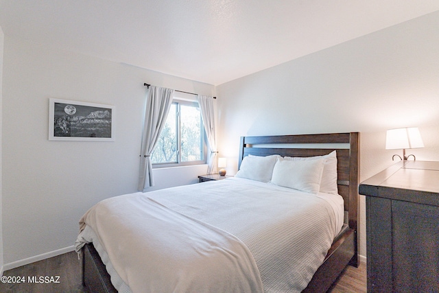 bedroom with vaulted ceiling and dark hardwood / wood-style floors