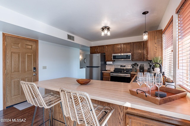 kitchen featuring kitchen peninsula, stainless steel appliances, dark wood-type flooring, and a wealth of natural light