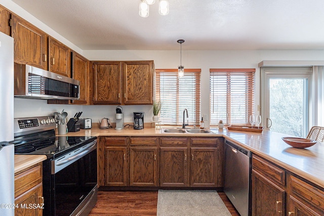 kitchen with sink, hanging light fixtures, stainless steel appliances, and dark hardwood / wood-style flooring