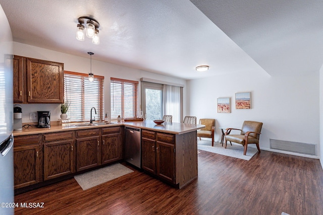 kitchen with kitchen peninsula, dishwasher, dark wood-type flooring, pendant lighting, and sink