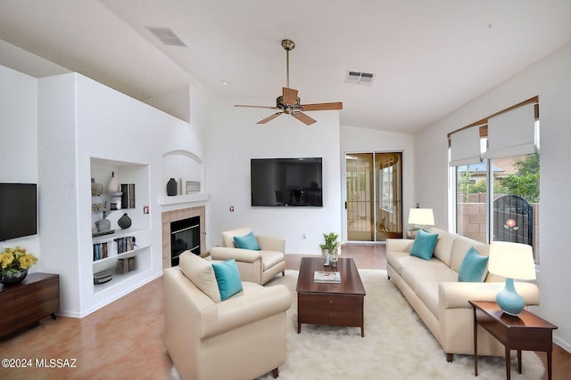 living room with built in features, vaulted ceiling, a tile fireplace, and ceiling fan