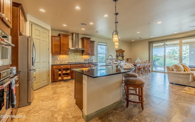 kitchen with appliances with stainless steel finishes, a kitchen bar, wall chimney range hood, and light tile patterned floors