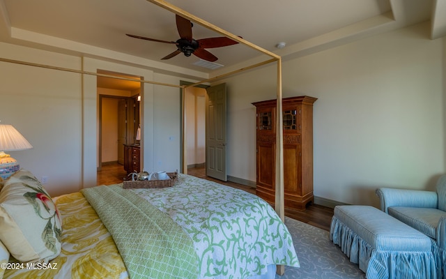 bedroom with visible vents, a tray ceiling, ceiling fan, and wood finished floors