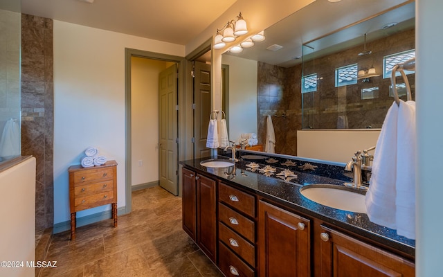 bathroom with double vanity, walk in shower, baseboards, and a sink