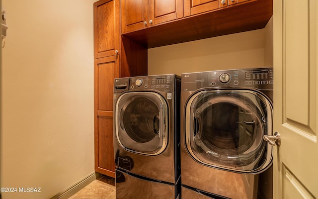 laundry area with tile patterned flooring, washing machine and dryer, and cabinet space