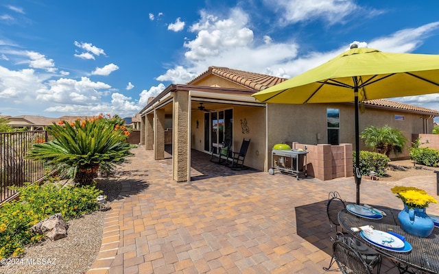 exterior space featuring ceiling fan, fence, a tile roof, stucco siding, and a patio area