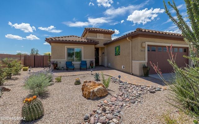 back of property with stucco siding, a tiled roof, a garage, and fence