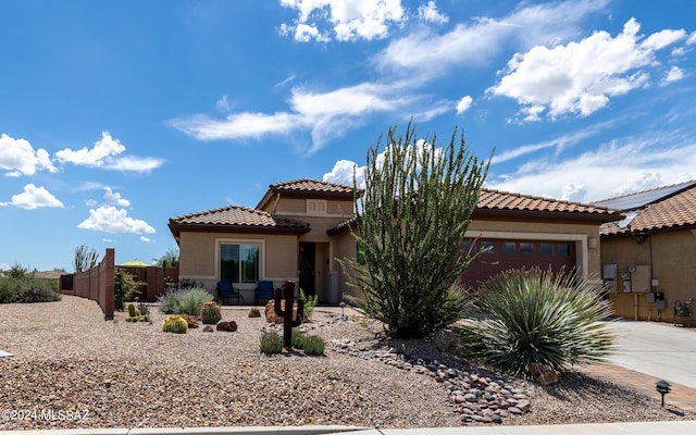 mediterranean / spanish house with fence, an attached garage, stucco siding, concrete driveway, and a tiled roof