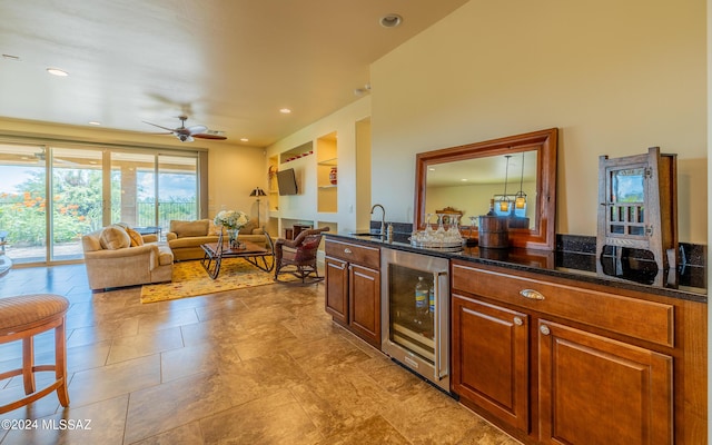 kitchen with dark stone countertops, a ceiling fan, beverage cooler, recessed lighting, and a sink