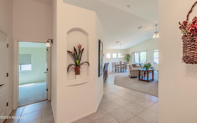 hallway featuring light carpet and high vaulted ceiling