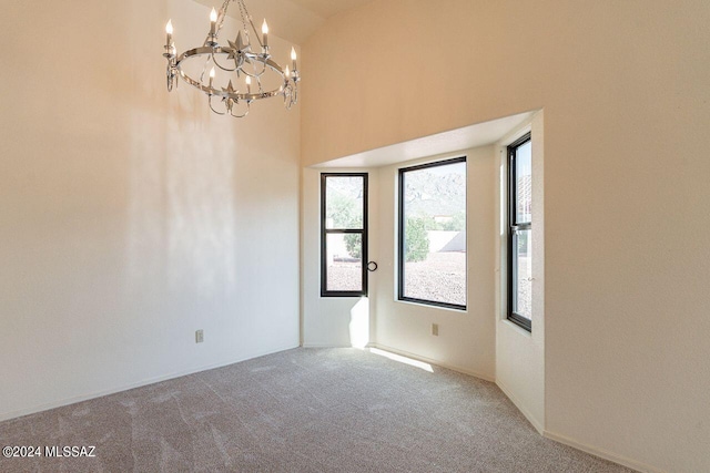 carpeted spare room with an inviting chandelier