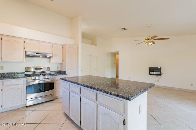 kitchen with gas stove, ceiling fan, high vaulted ceiling, light tile patterned floors, and a center island