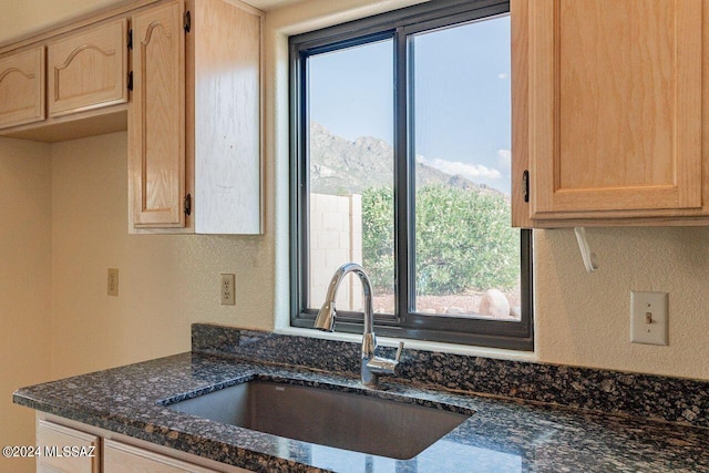 kitchen featuring dark stone counters, light brown cabinets, sink, and a wealth of natural light