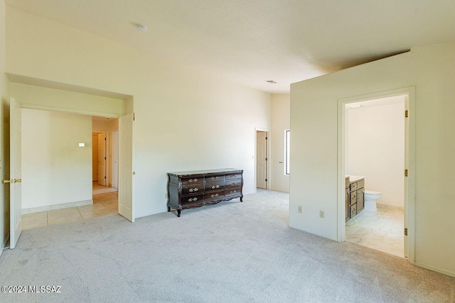 unfurnished bedroom featuring light carpet and ensuite bath