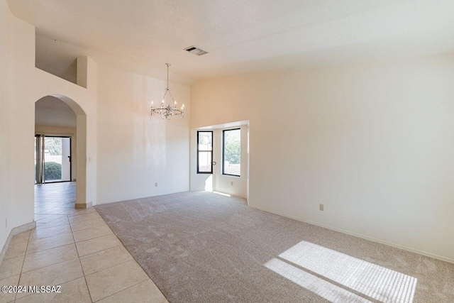 empty room featuring light tile patterned floors, high vaulted ceiling, and an inviting chandelier