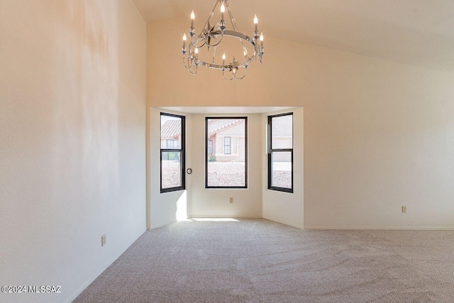 carpeted spare room featuring vaulted ceiling and an inviting chandelier