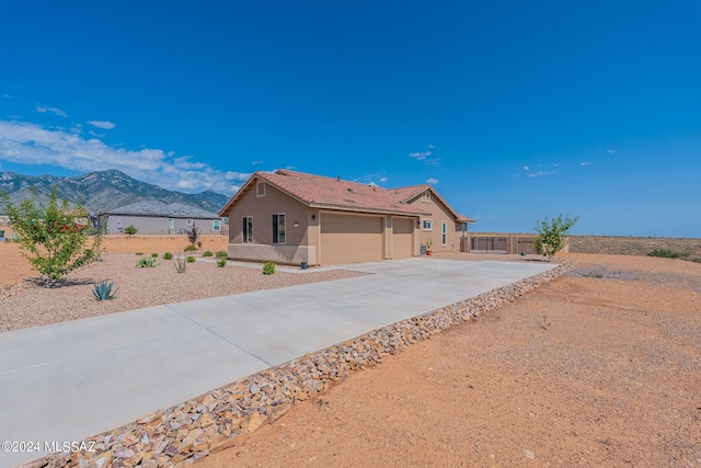 ranch-style home with driveway, a tile roof, fence, a mountain view, and stucco siding