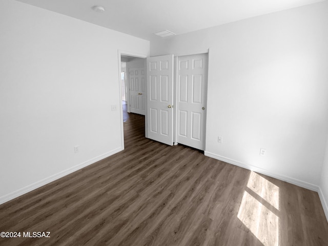 unfurnished bedroom with dark hardwood / wood-style floors and a closet