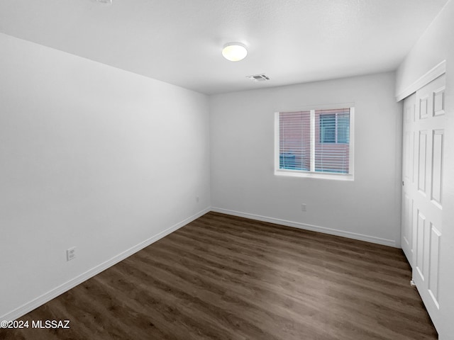 unfurnished bedroom with dark hardwood / wood-style floors and a closet