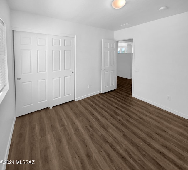 unfurnished bedroom with dark hardwood / wood-style flooring and a closet