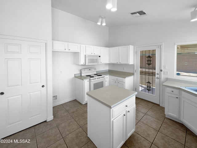 kitchen with light tile patterned floors, white cabinets, white appliances, and a kitchen island