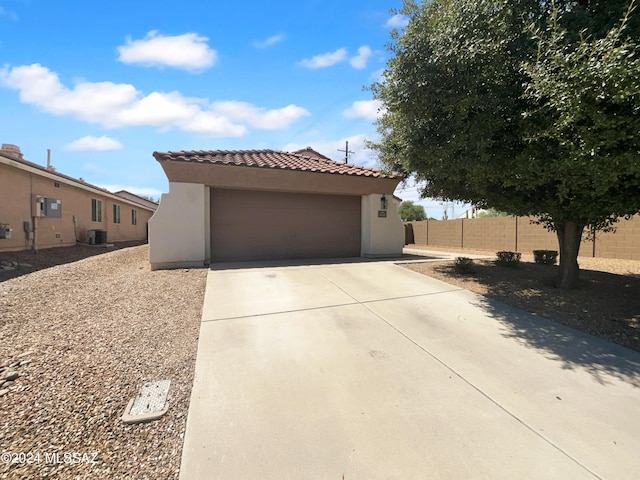 view of front of house with a garage, cooling unit, and an outdoor structure