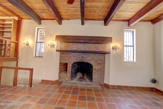 unfurnished living room featuring ceiling fan, wood ceiling, tile patterned flooring, a fireplace, and beamed ceiling