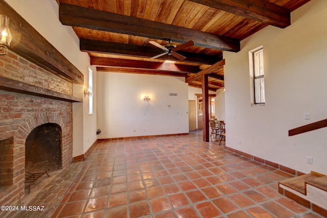 unfurnished living room with ceiling fan, a brick fireplace, tile patterned floors, wooden ceiling, and beamed ceiling