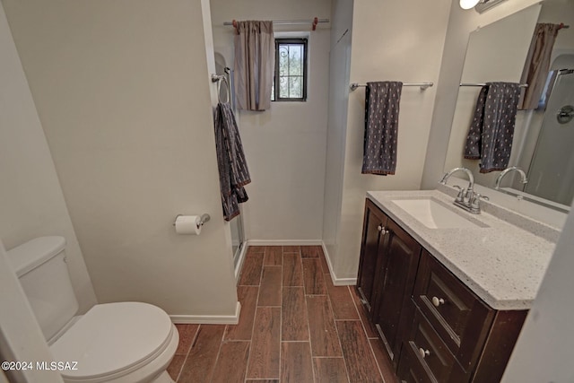 bathroom with hardwood / wood-style floors, toilet, walk in shower, and vanity