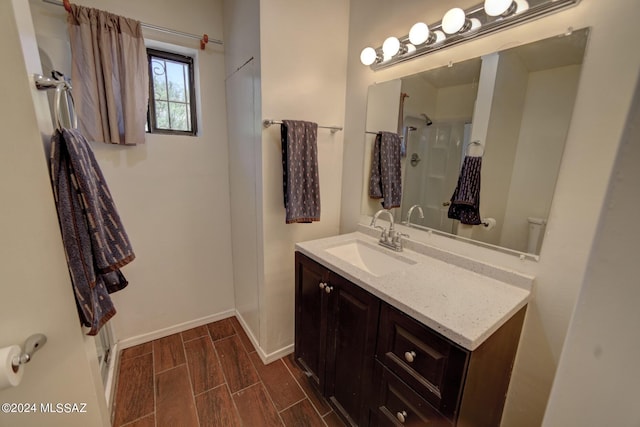 bathroom with a shower, wood-type flooring, vanity, and toilet