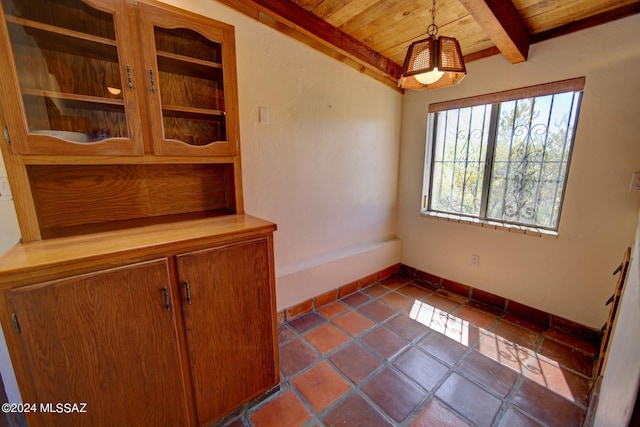 unfurnished dining area with wooden ceiling, tile patterned floors, and beamed ceiling