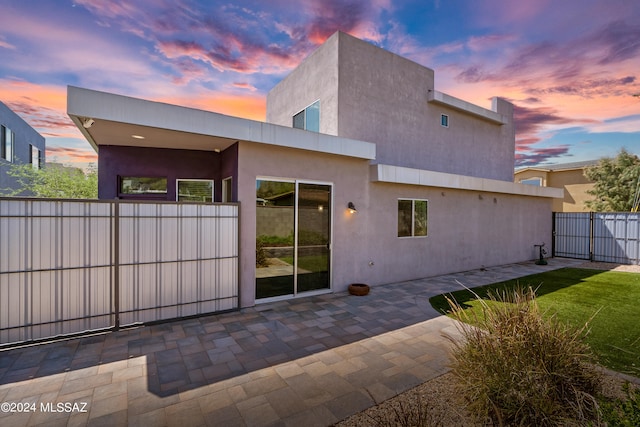 back house at dusk featuring a patio area