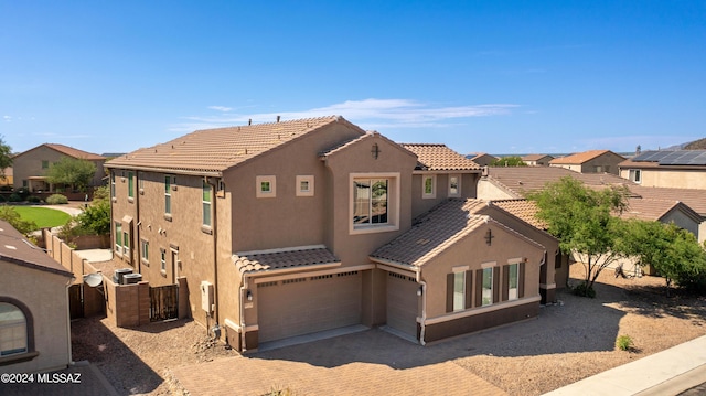 view of front of property featuring decorative driveway, an attached garage, a tile roof, and stucco siding