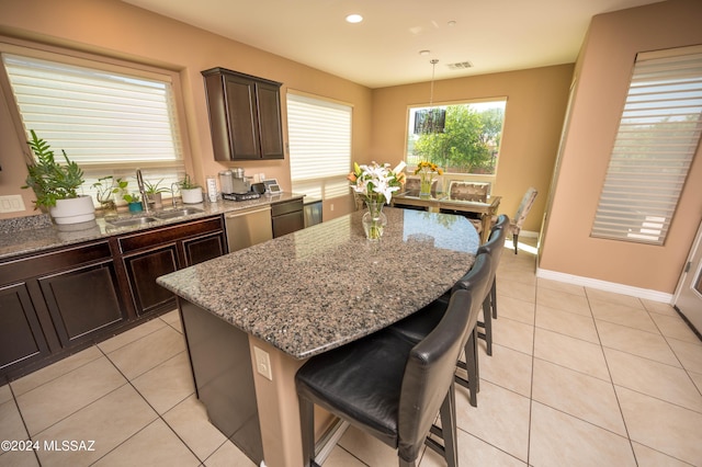 kitchen with decorative light fixtures, sink, a kitchen breakfast bar, a center island, and stainless steel dishwasher